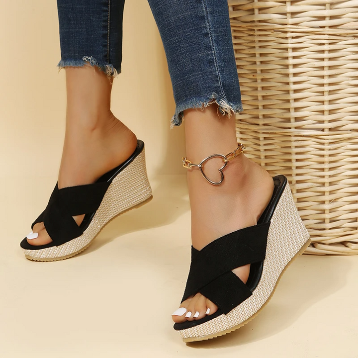 Women's black suede Cora wedge slide sandals with crossed front straps and a textured straw-look sole.