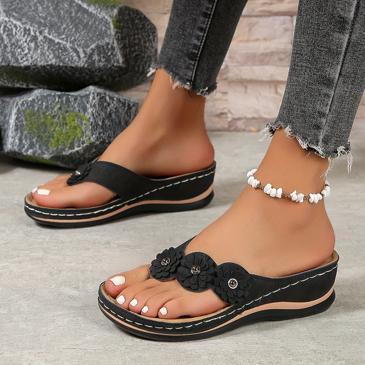 Black Pippa floral slide sandals with layered flower details, contrast stitching, and a low sole.