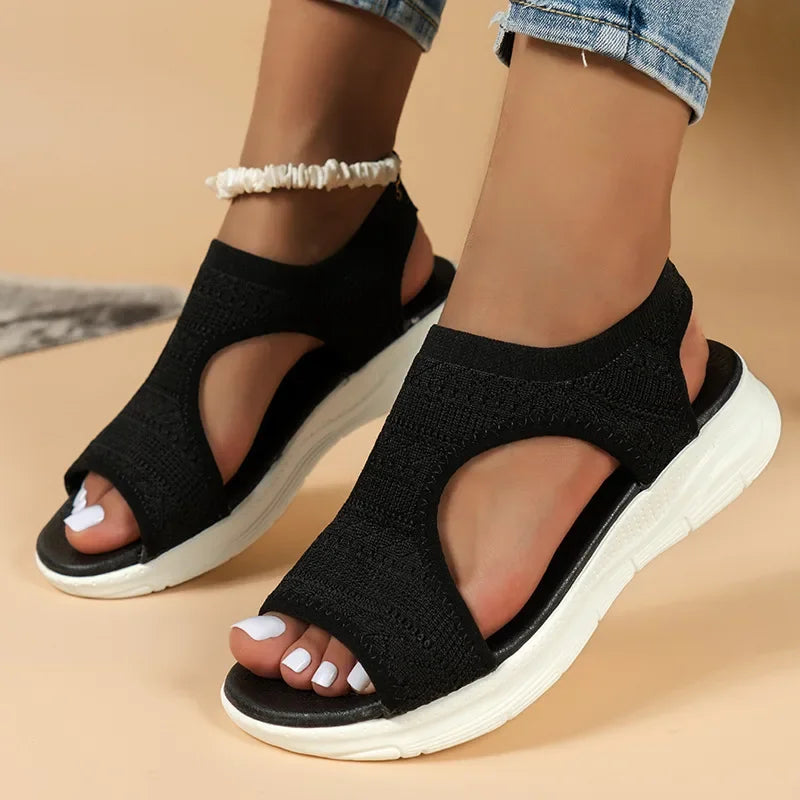Women's black knit slip-on Soleil sandals with open toe, side cutouts, and a cushioned white sole.