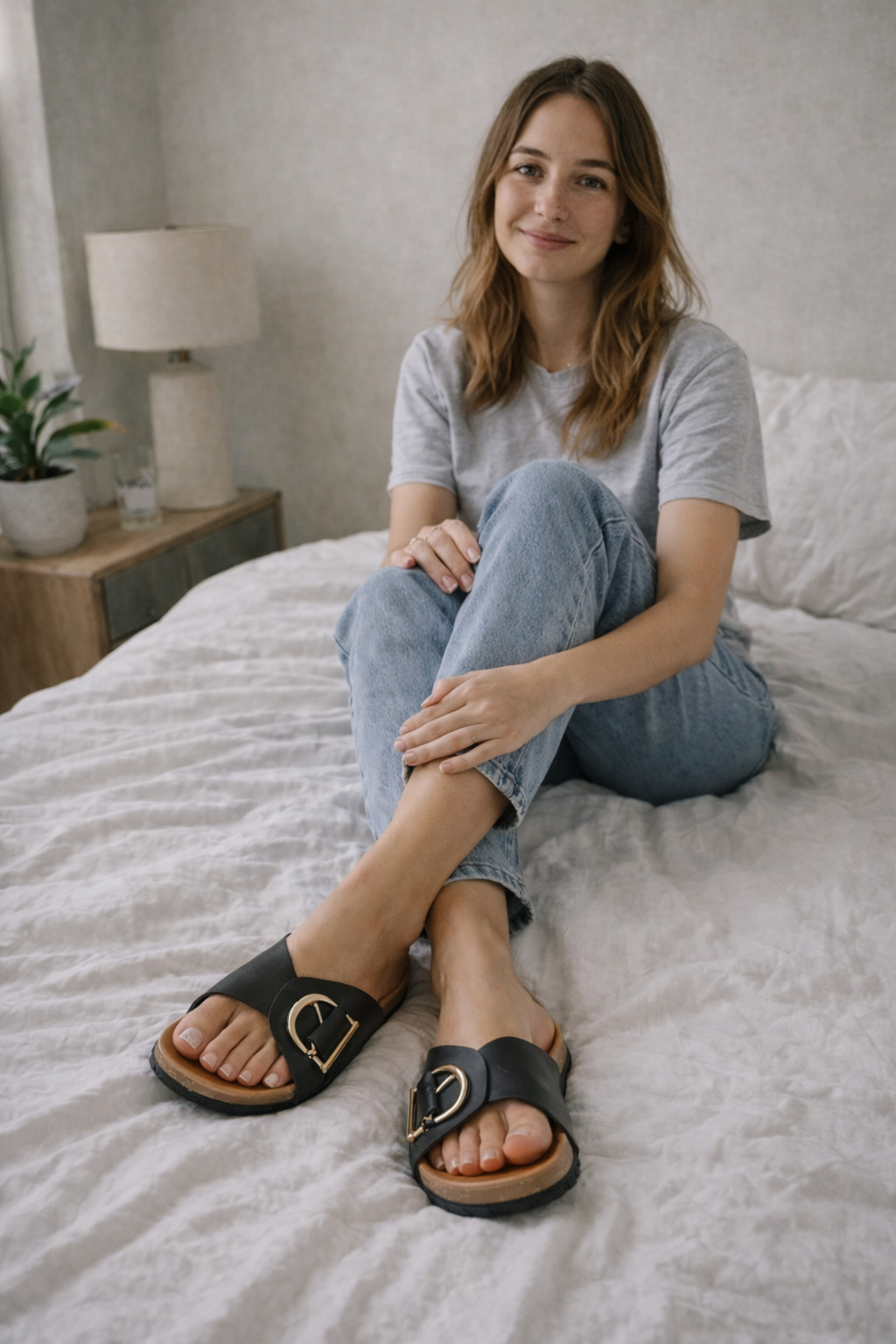 Woman wearing black Sylvie buckle slide sandals with gold-tone hardware, cork footbed, and wide straps.