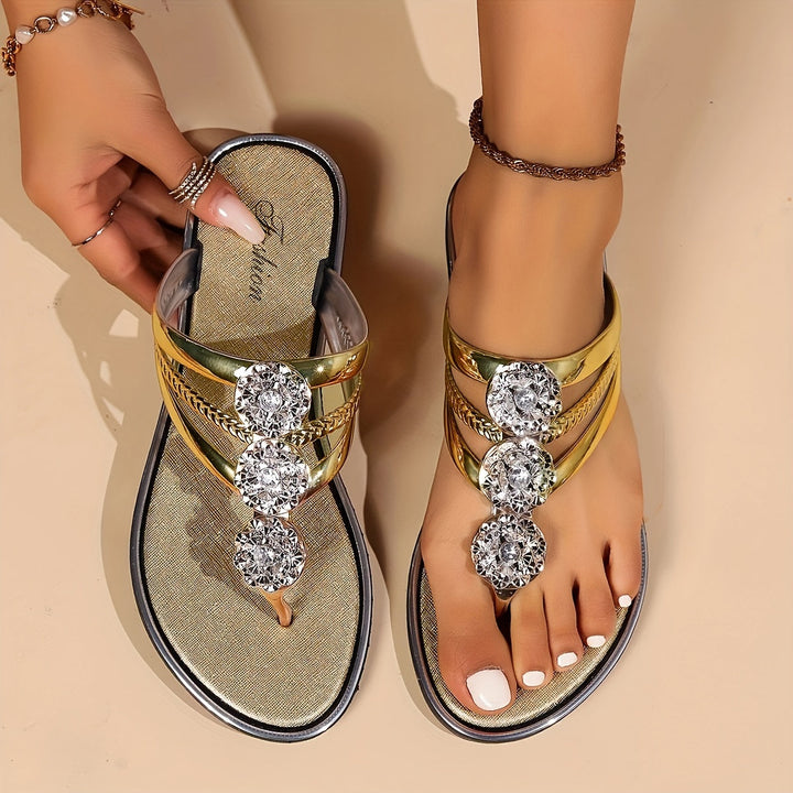 Vespera women's metallic gold thong sandals with sparkling rhinestone floral accents and a flat sole.