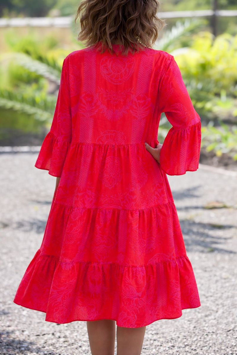 Woman in a bright red Agnes tiered boho V-neck dress with bell sleeves and a subtle pattern.