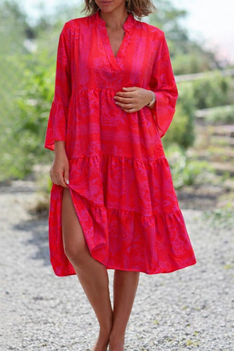 Woman in a bright red and pink floral tiered boho V-neck midi dress with long sleeves.