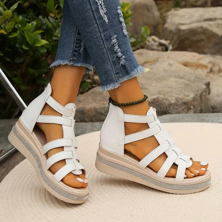 White platform gladiator sandals with strappy upper, open toe, and embellished beige sole.