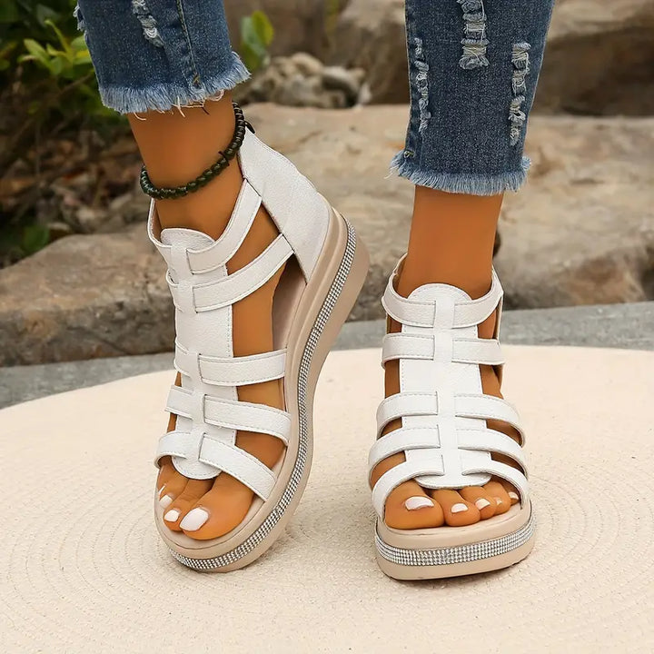 White platform gladiator sandals with strappy upper, open toe, and rhinestone-embellished sole.
