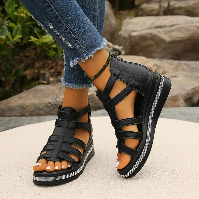 Black platform gladiator sandals with strappy upper, open toe, and rhinestone trim on a model.