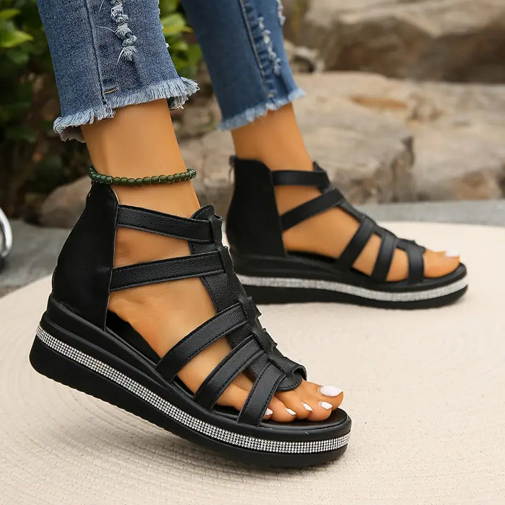 Black women's platform gladiator sandals with strappy upper, open toe, and rhinestone-embellished wedge sole.
