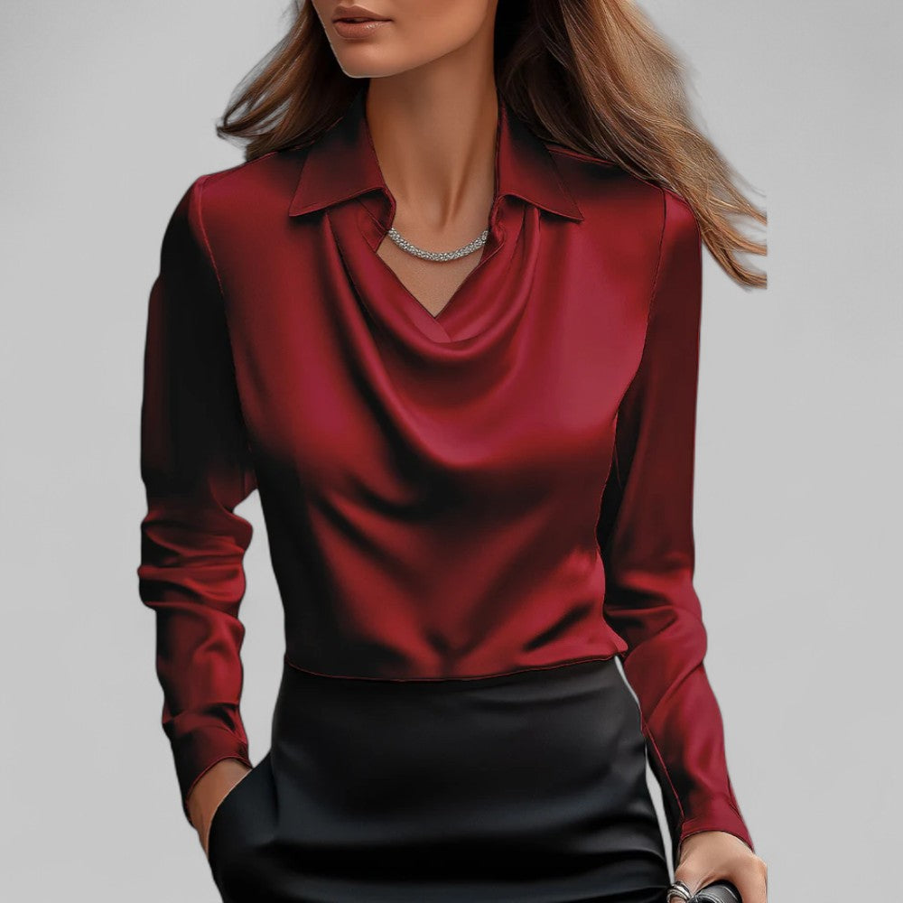 Red satin Aria blouse with a draped cowl neck and long sleeves, tucked into black trousers.
