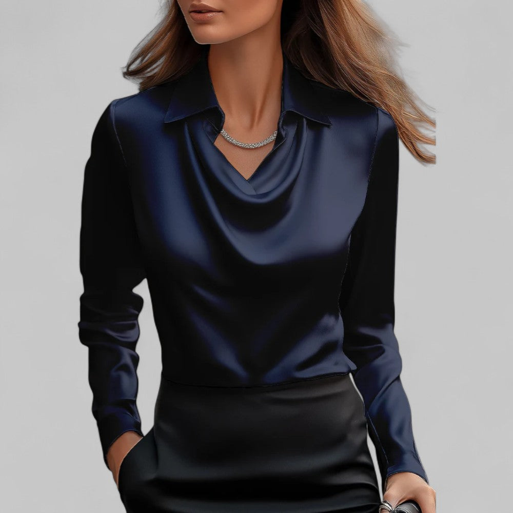 Woman wearing the Aria navy blue satin blouse with a draped cowl neckline and long sleeves.