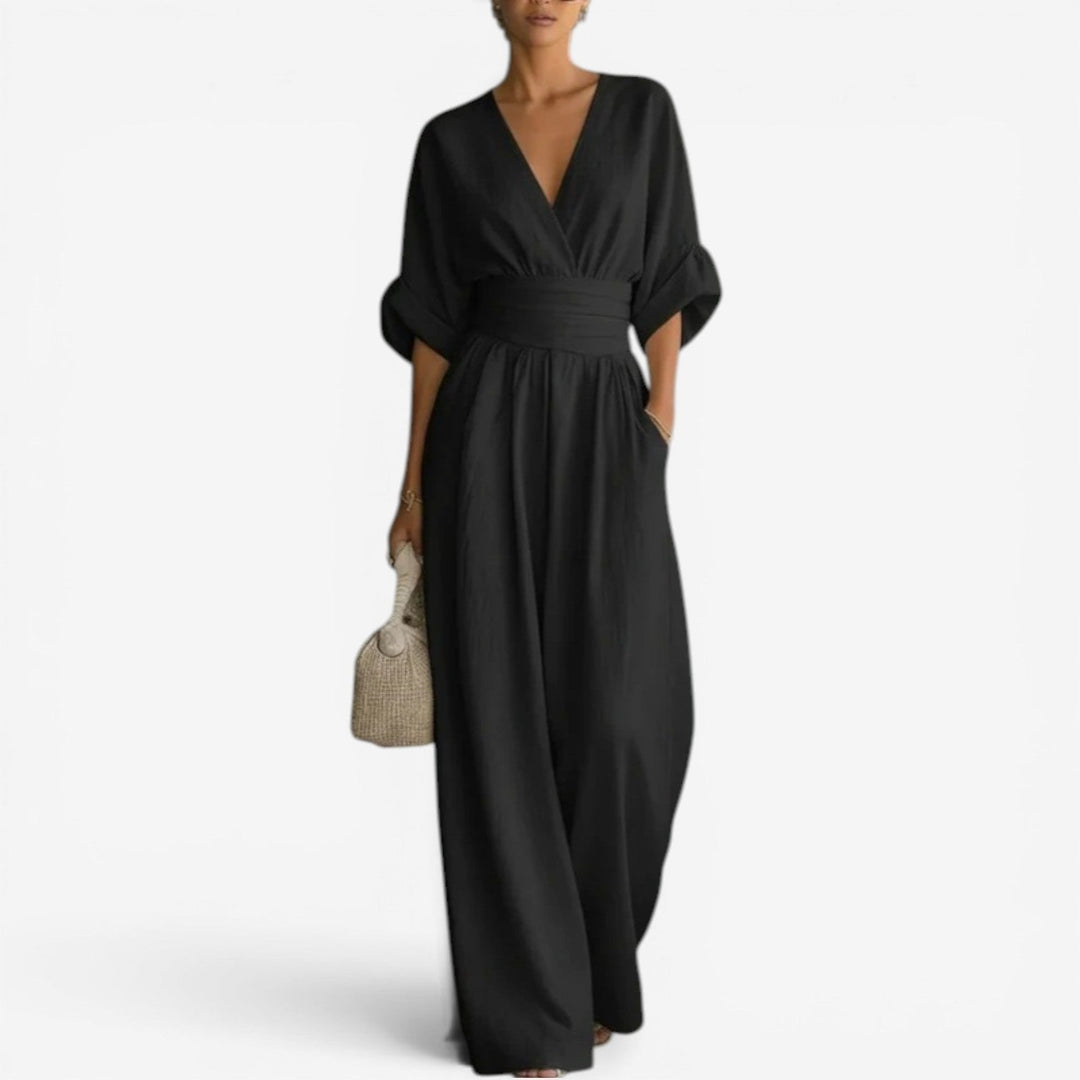 Black V-neck jumpsuit with wide sleeves, a cinched waist, and flowing wide-leg trousers.