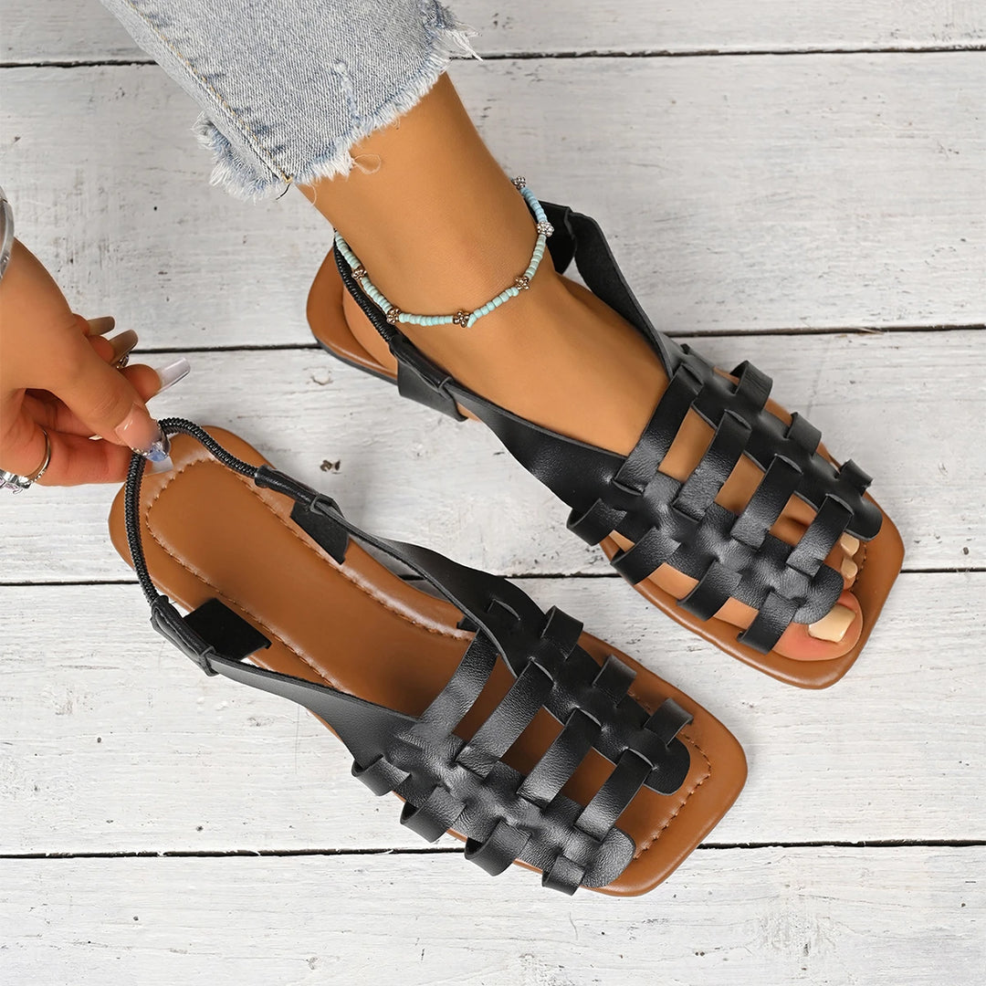Ava black woven fisherman flat sandals with brown soles on a model.