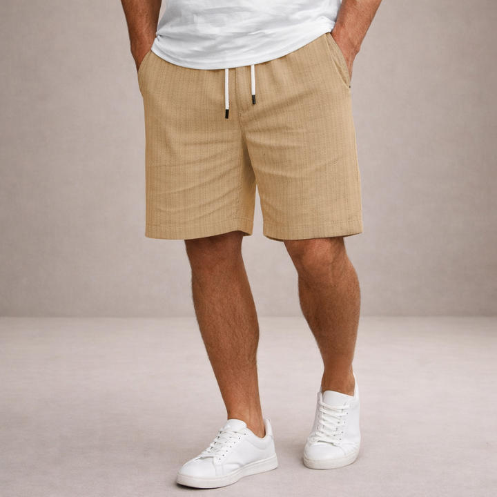 Men's Brandon tan linen drawstring summer shorts with side pockets and white drawstrings, worn with white sneakers.