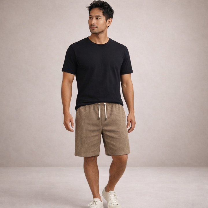 Man wearing Brandon men's tan drawstring linen summer shorts with a black tee and white sneakers.