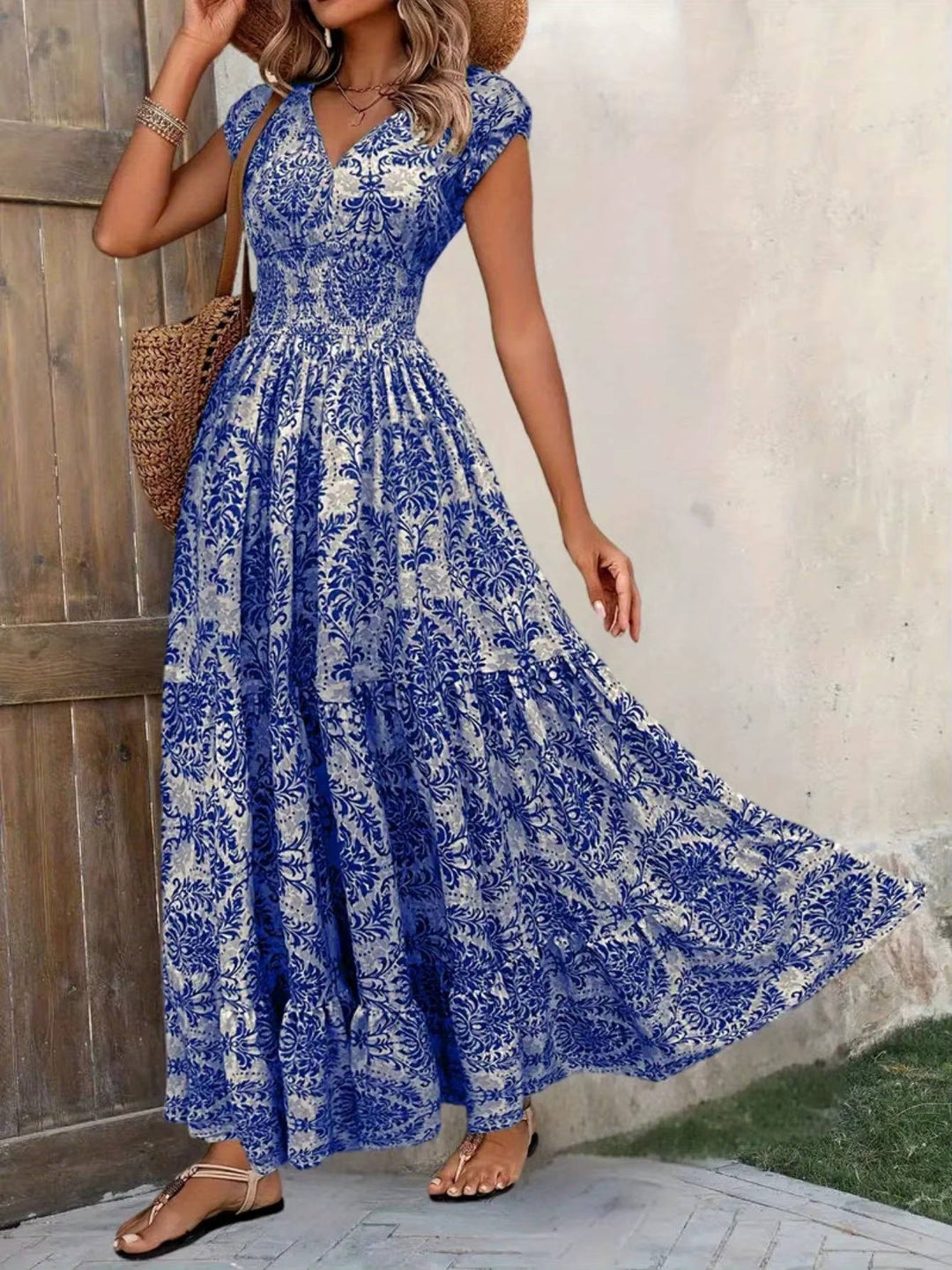 Women's blue and white ornate print V-neck maxi boho dress with flutter sleeves and tiered skirt.