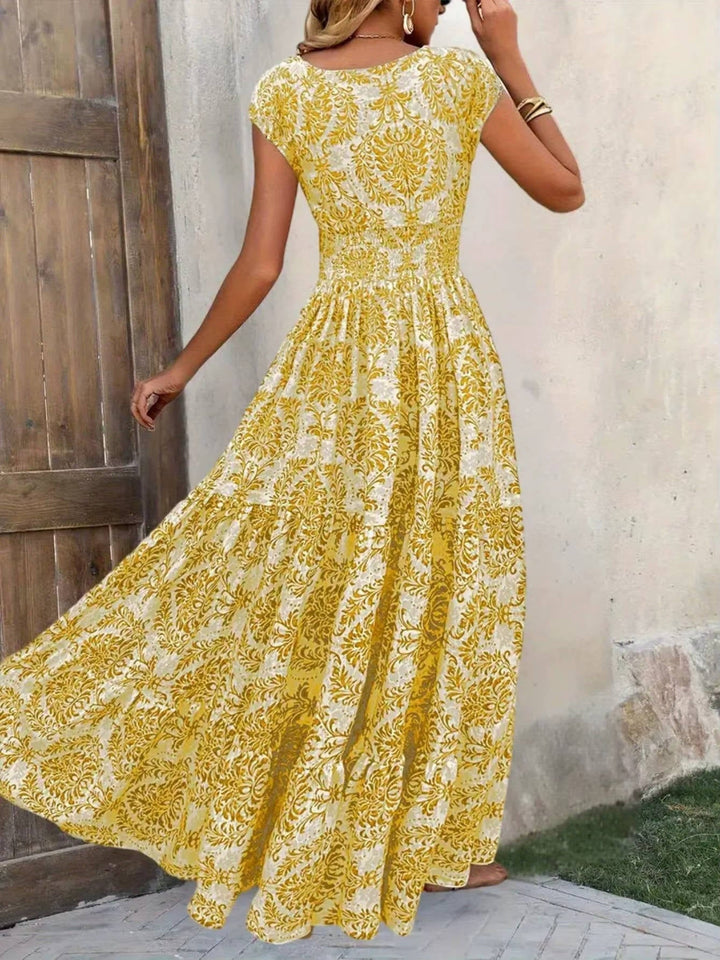 Women's yellow V-neck maxi boho dress with white ornate print and flutter sleeves.