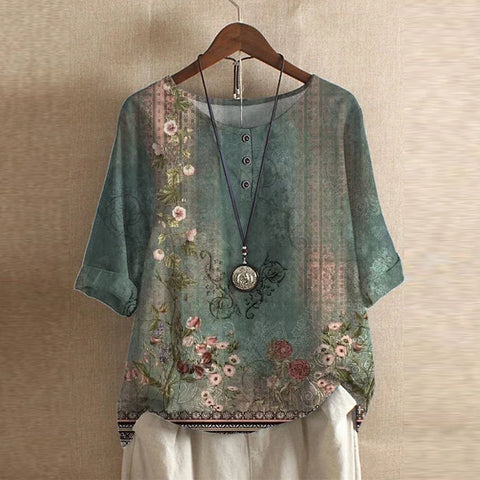Sage green floral blouse with a relaxed drape, three-quarter sleeves, and button-front detail on a round neckline.