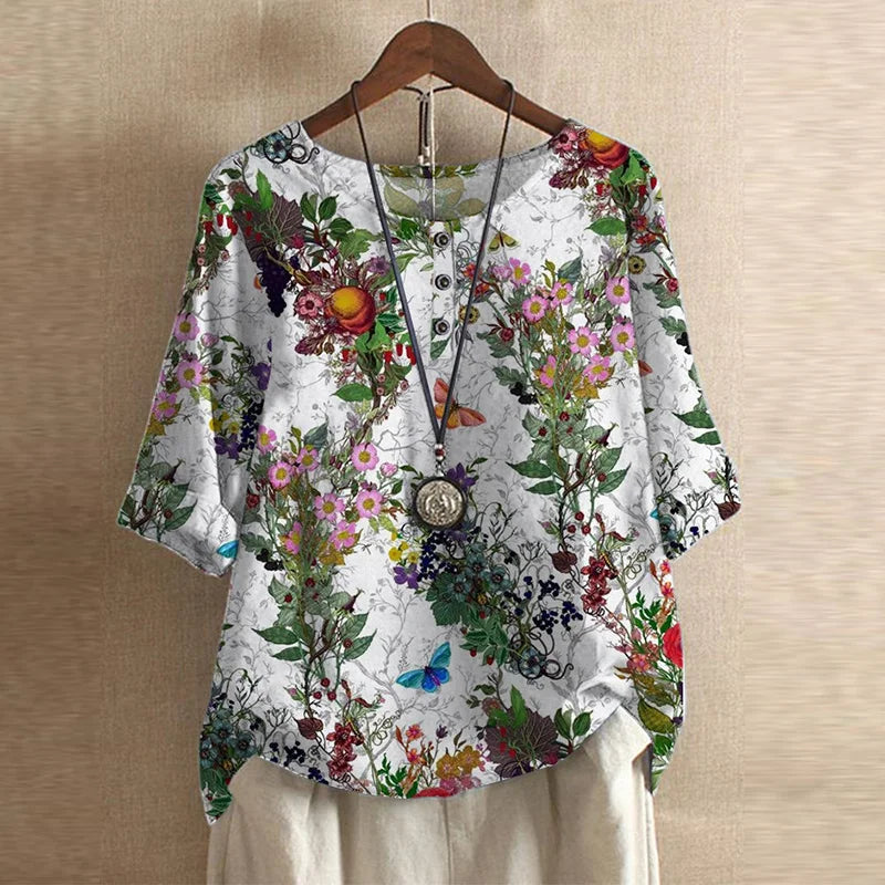 Women's white blouse featuring a vibrant floral print, three-quarter sleeves, and a button-front neckline.