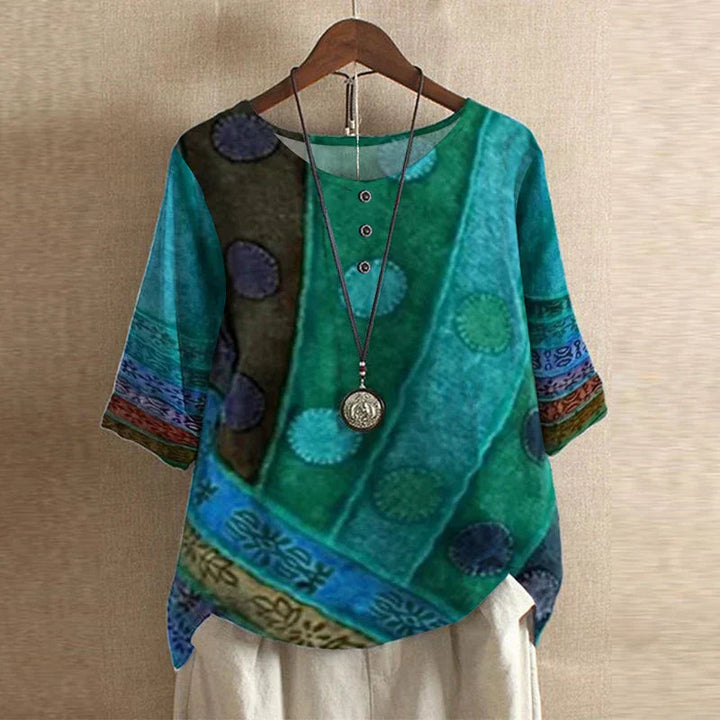 Relaxed-fit teal floral blouse with a round neckline, button-front detail, and three-quarter sleeves.