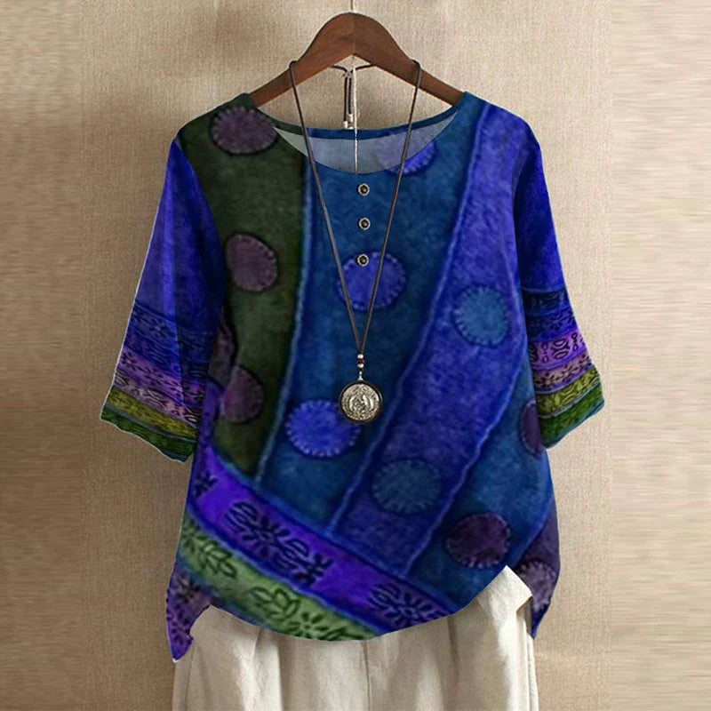 Blue floral button-down blouse with a relaxed, draped fit and three-quarter sleeves on a wooden hanger.
