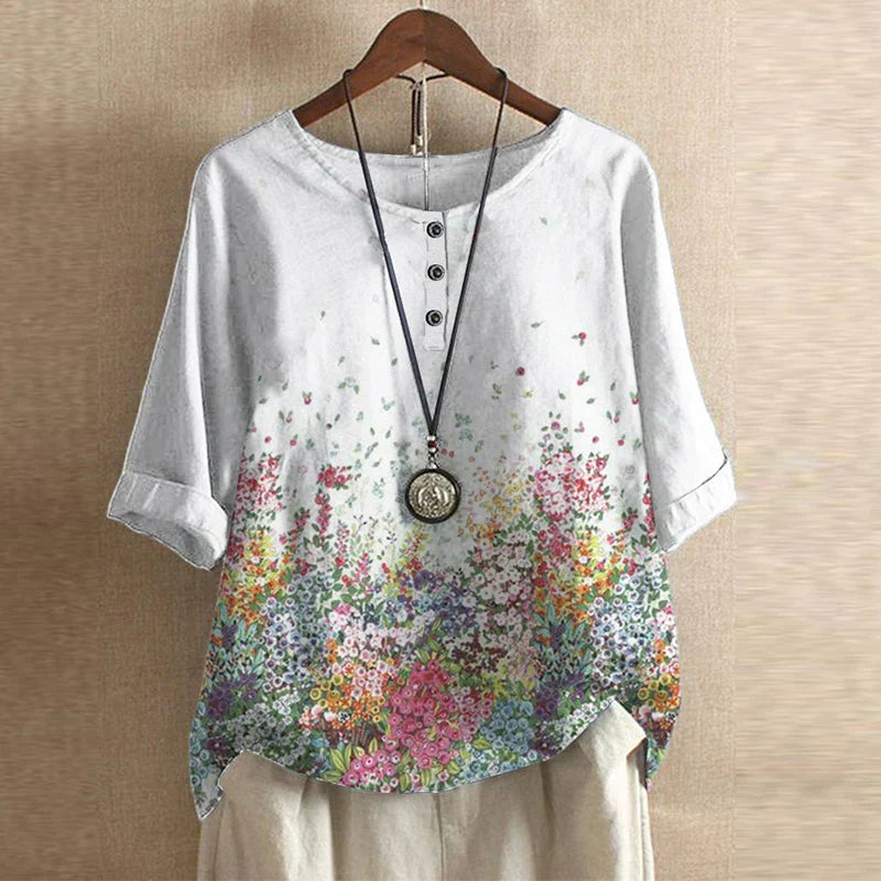 White floral button-down blouse with a relaxed, draped fit and three-quarter sleeves on a wooden hanger.
