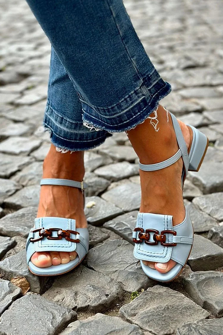 Camille light blue heeled sandals with tortoise link detail, worn with denim on cobblestone.
