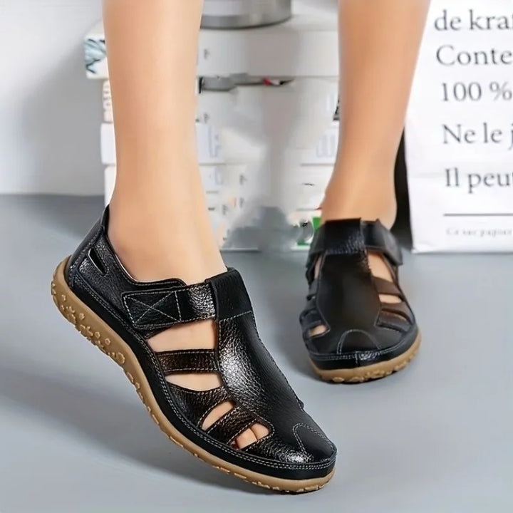 Black leather Clara closed-toe fisherman sandals with textured tan soles.