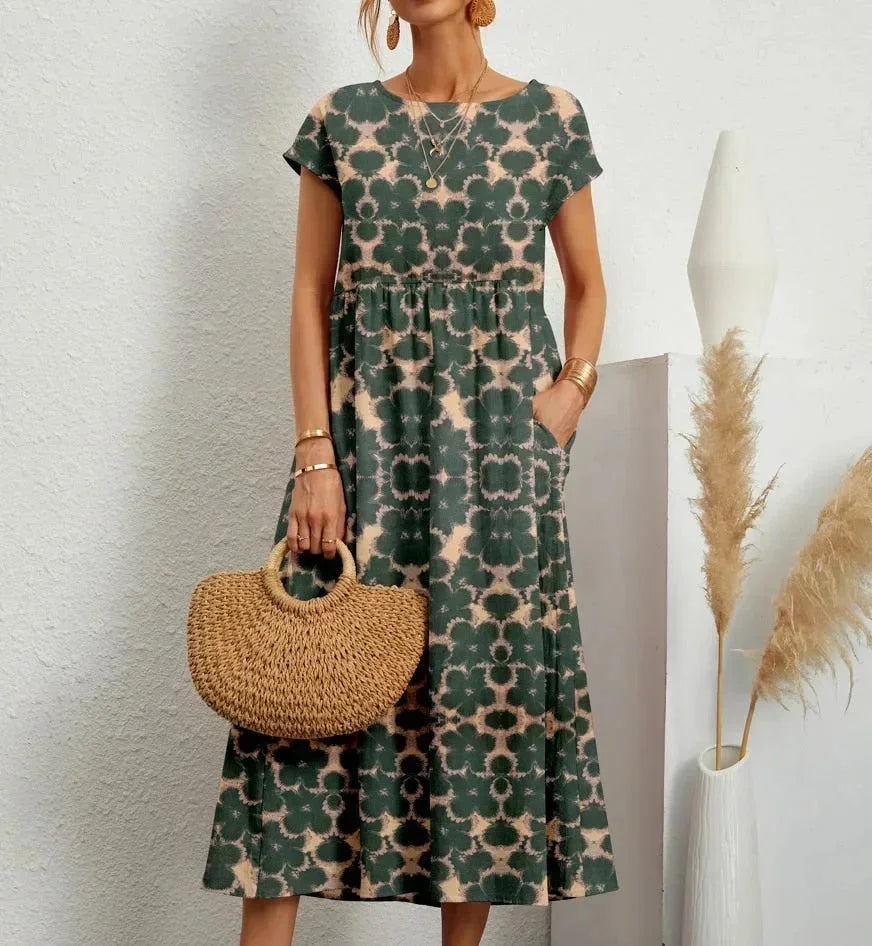Clara floral cotton midi dress with short sleeves, practical pockets, and a vibrant green and beige print.
