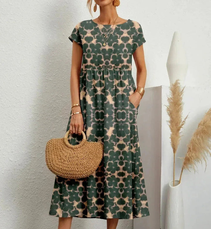 Clara floral cotton midi dress with short sleeves, practical pockets, and a vibrant green and beige print.