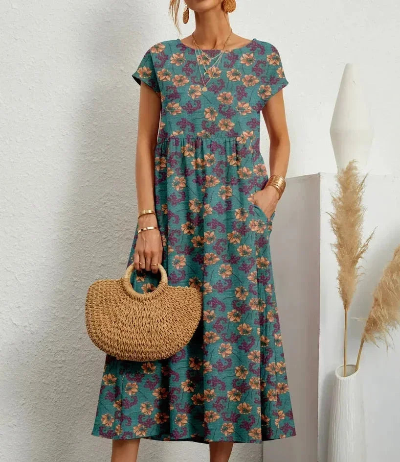 Clara women's floral cotton midi dress in vibrant teal with short sleeves and practical pockets.