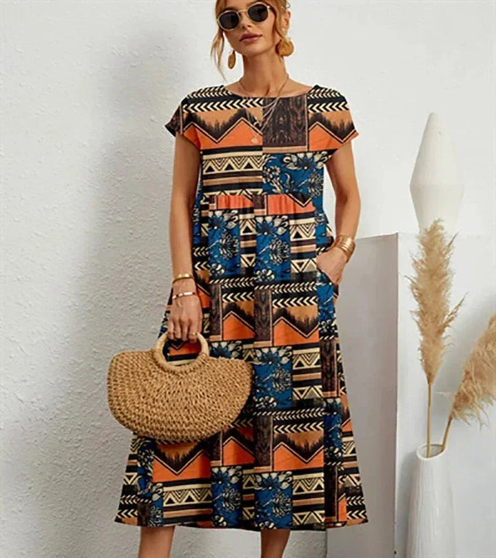 Clara women's floral cotton midi dress with short sleeves, practical pockets, and a vibrant print.