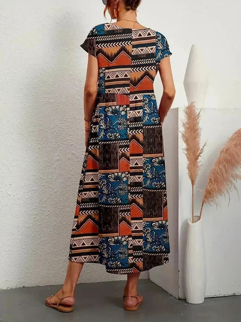 Clara floral cotton midi dress with vibrant patchwork print, short sleeves, and practical pockets.