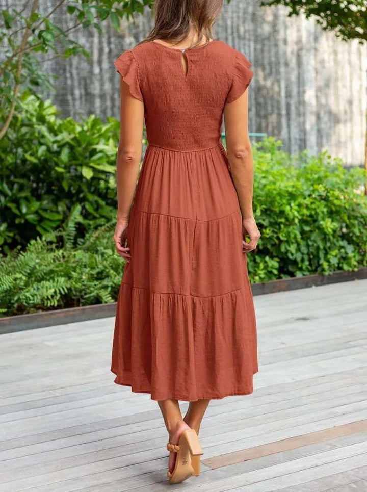 Clara women's rust tiered cap sleeve midi dress with a fitted bodice and flowing skirt, perfect for graceful movement.