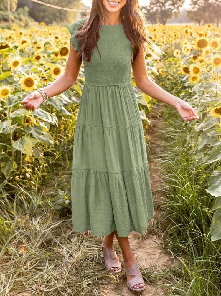Clara Women's Tiered Cap Sleeve Midi Dress in sage green, featuring a fitted bodice and flowing skirt in a sunflower field.