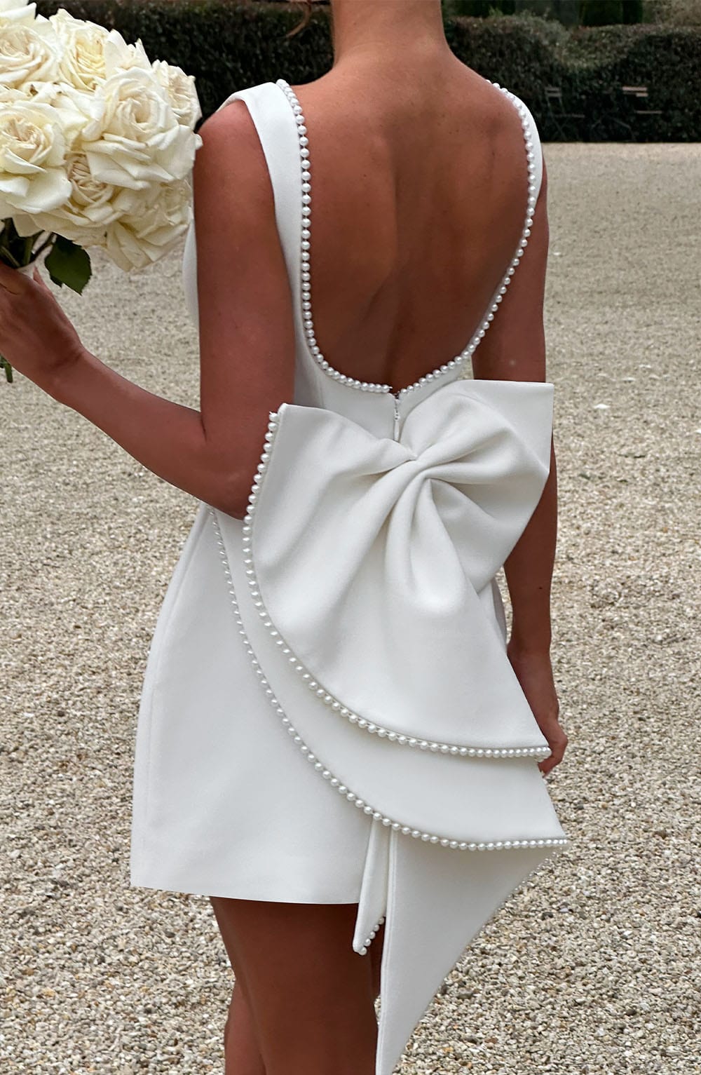 White Colette mini dress with a low back, pearl trim, and a large structured bow.