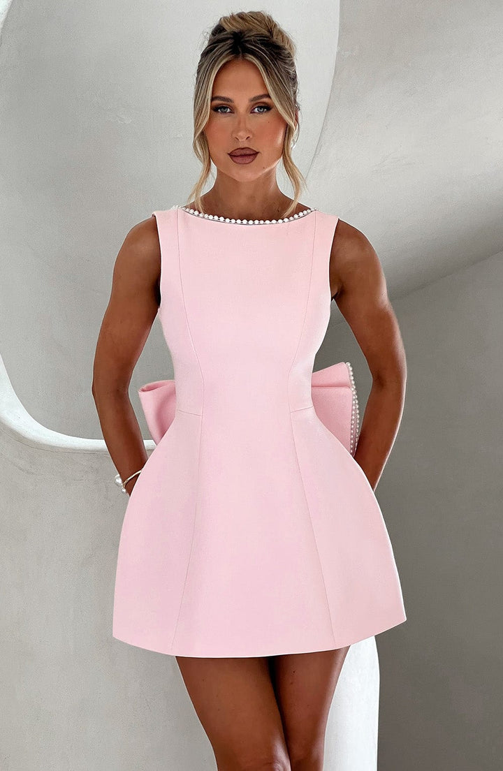 Pink Colette sleeveless structured mini dress with pearl-trimmed neckline and large back bow.