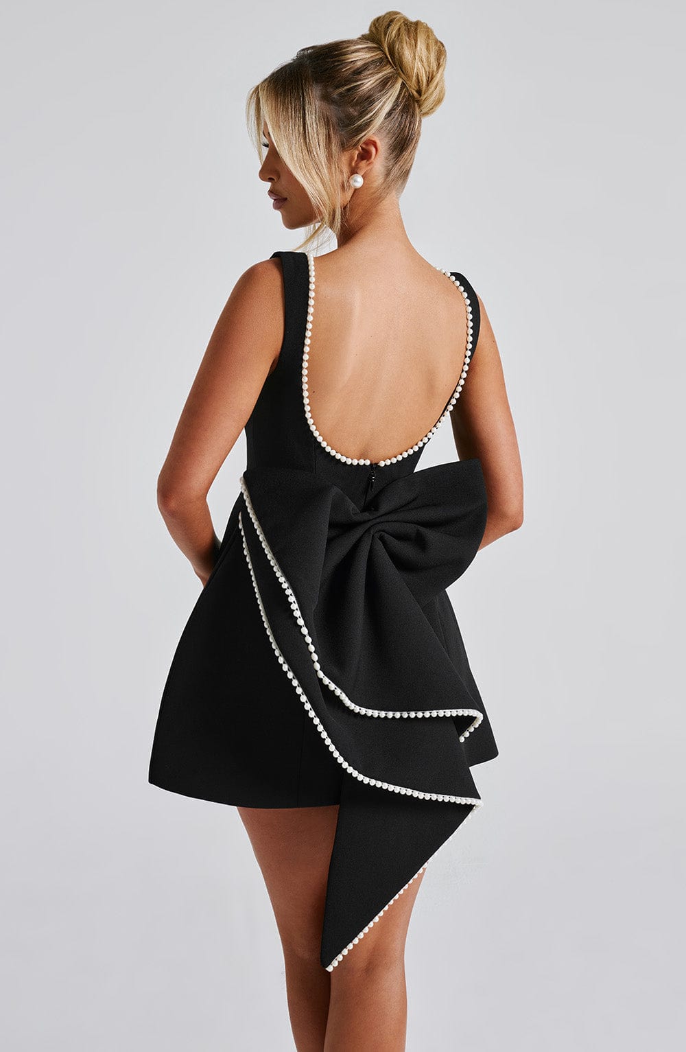 Black Colette mini dress with a low back, pearl trim, and a large structured bow.