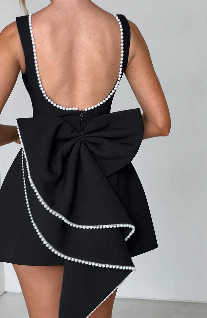 Back of the black Colette mini dress featuring a low scoop back and large bow trimmed with white pearls.
