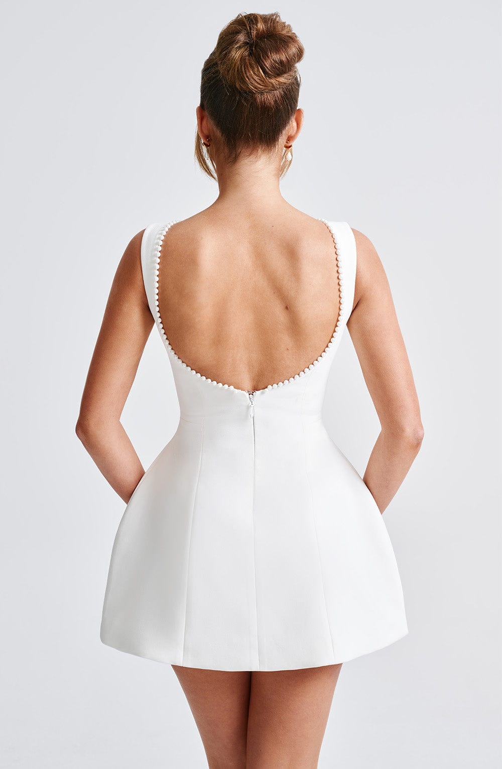 Back view of the white Colette structured mini dress featuring a low open back with delicate pearl trim.