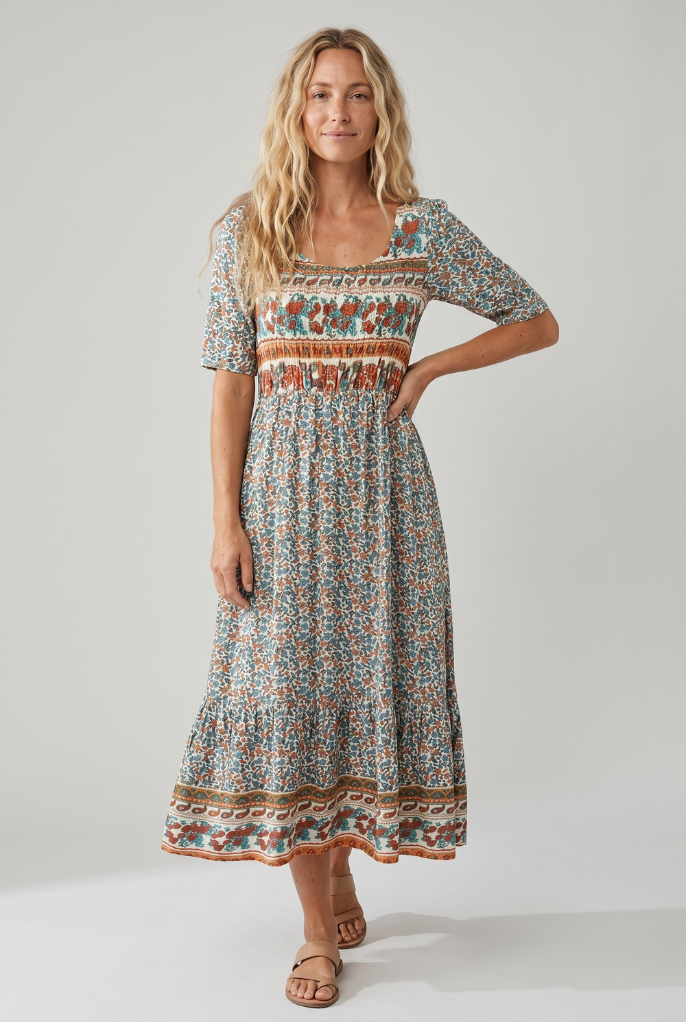 Woman in a square neck boho printed midi dress with a shirred bodice and tiered skirt.