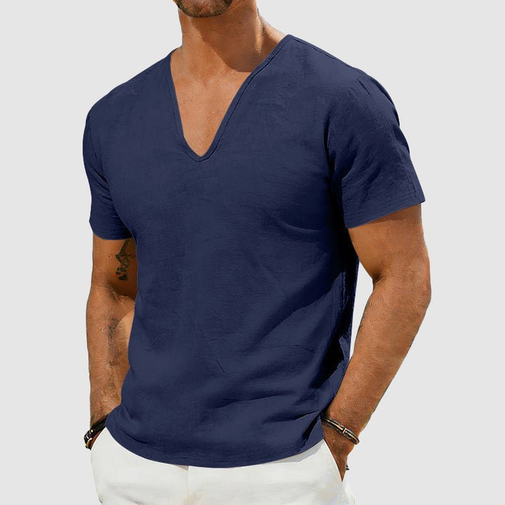 Men's Declan navy short sleeve linen V-neck shirt, worn with white pants.