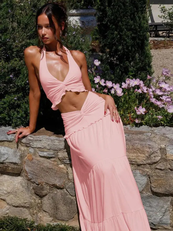 Woman in a pink halter crop top and matching tiered maxi skirt.