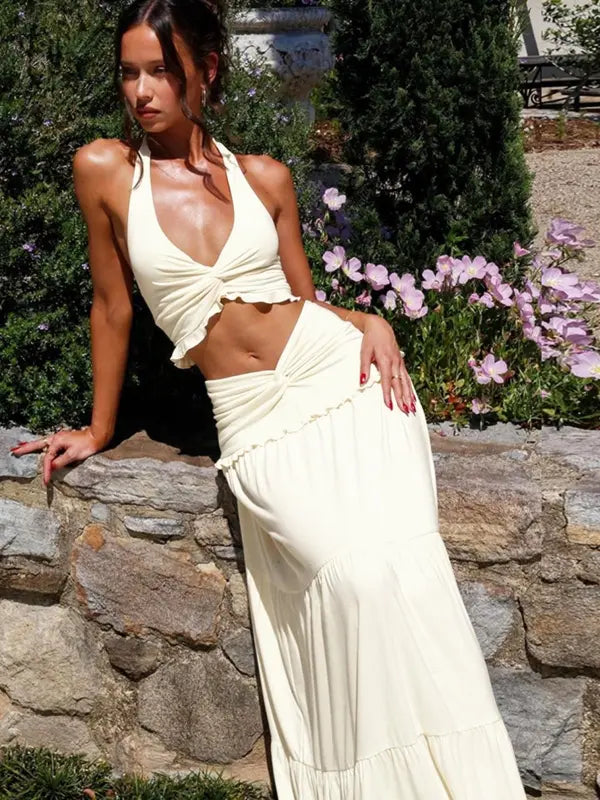 Woman in cream Delilah plunge halter top and matching tiered maxi skirt.