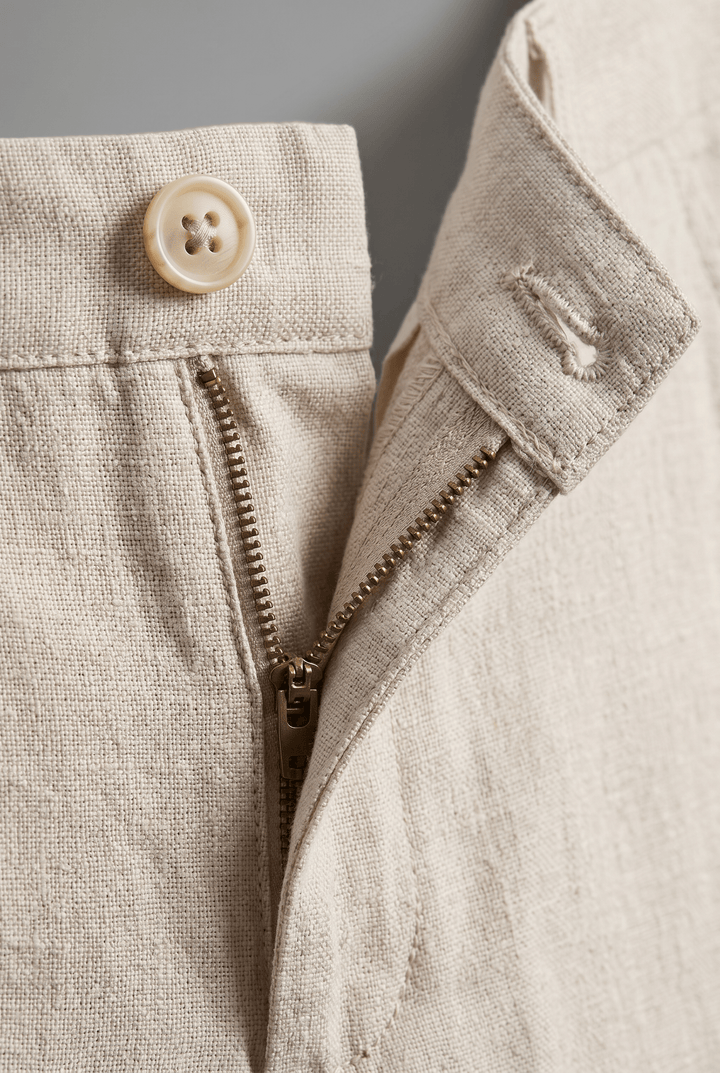 Close-up of Drew Men's Slim Fit Linen Chinos in a natural hue, showcasing the button, zip closure, and textured fabric.