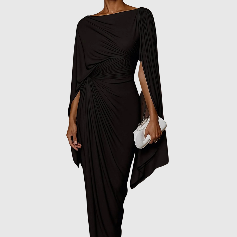 Genevieve black pleated maxi dress with asymmetric cape sleeves, holding a white clutch.