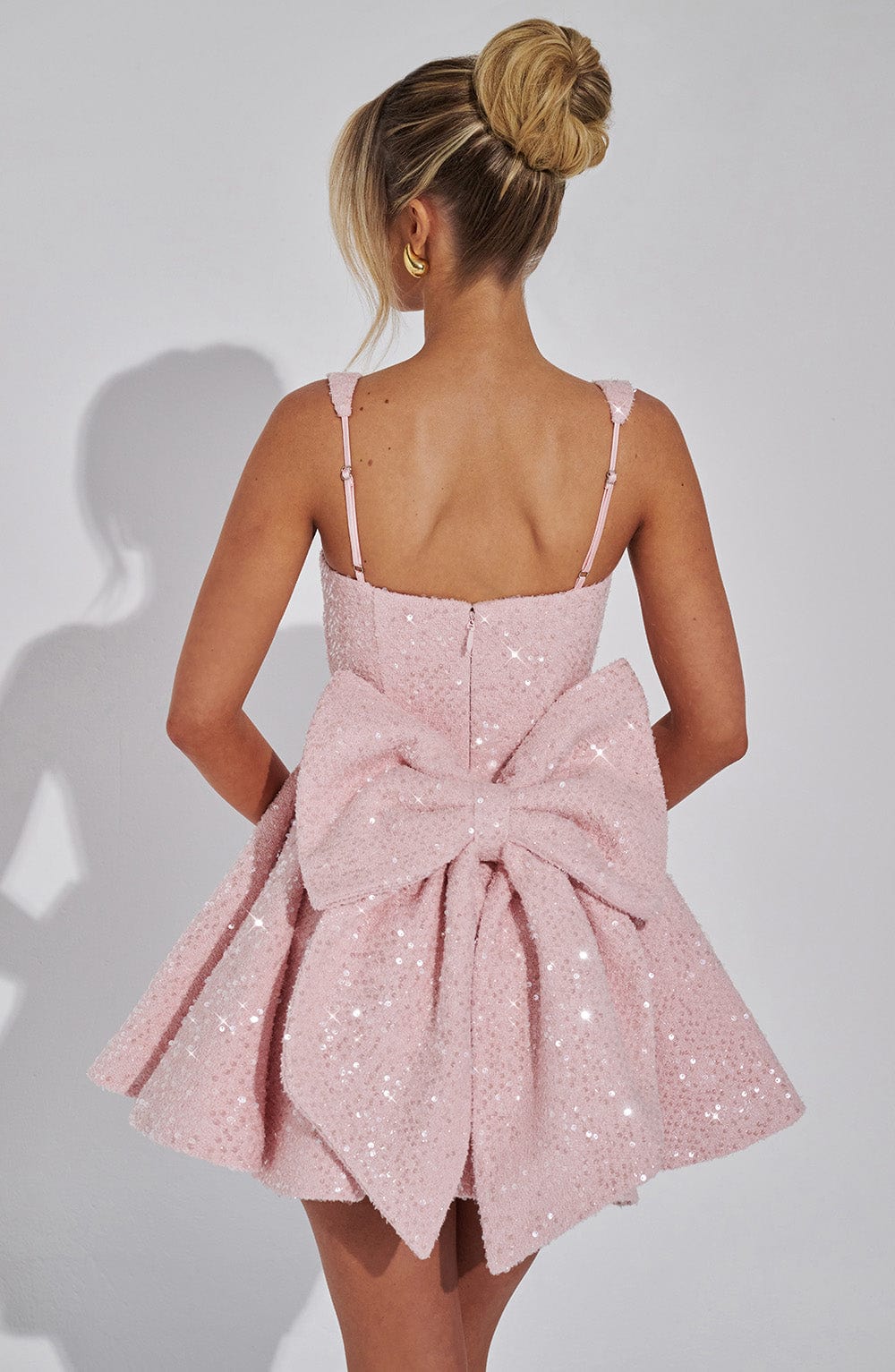 Back view of the pink Giselle sequin mini dress featuring a large bow detail.