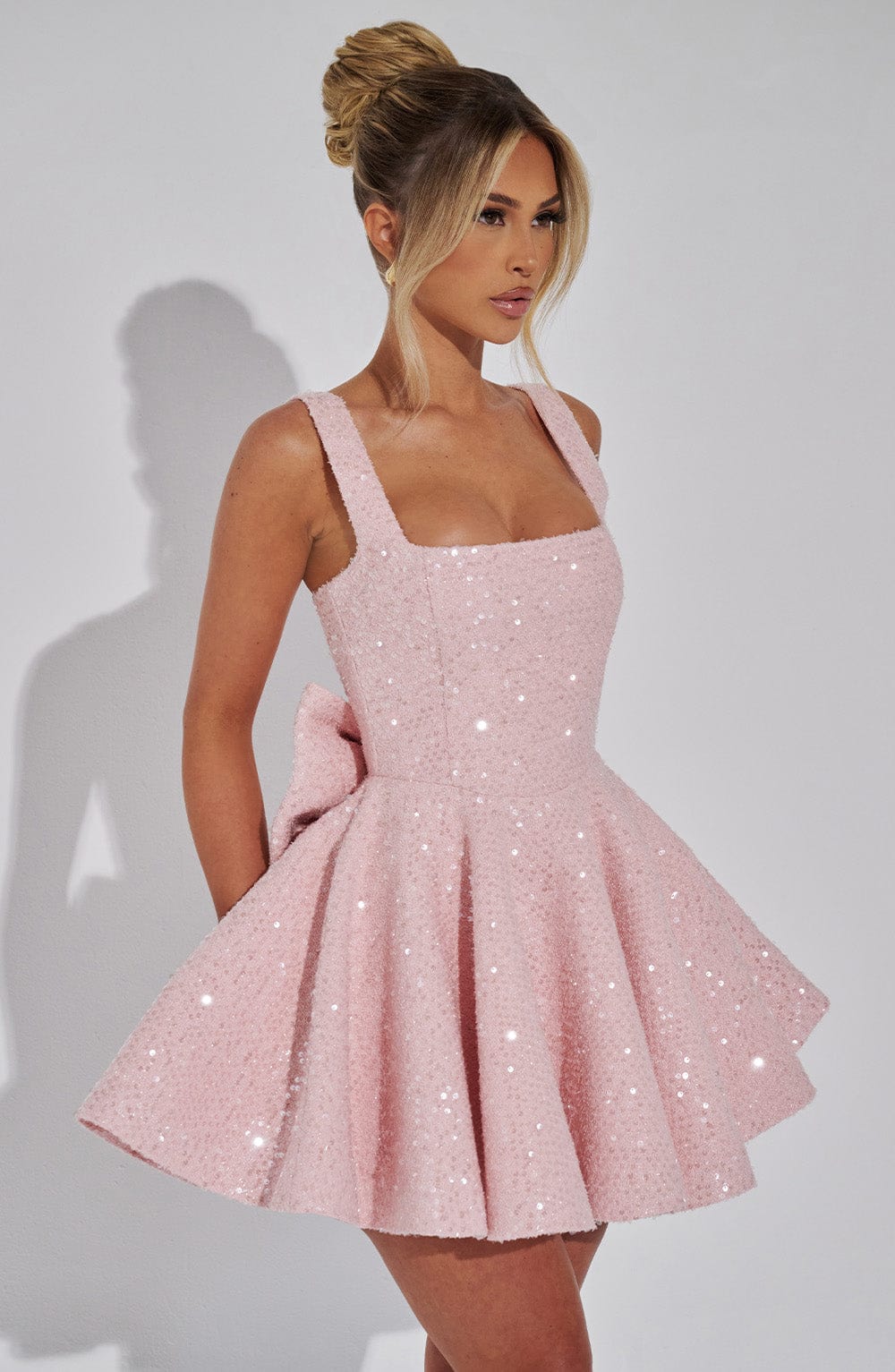 Pink sequin mini dress with a square neckline, flared skirt, and back bow detail.