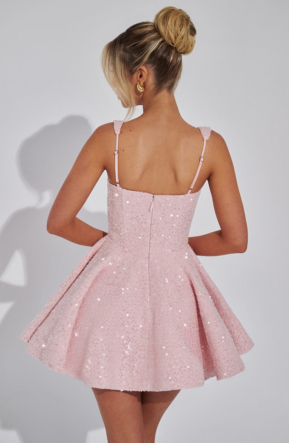 Back view of the pink Giselle sequin mini dress with a flared skirt and thin straps.