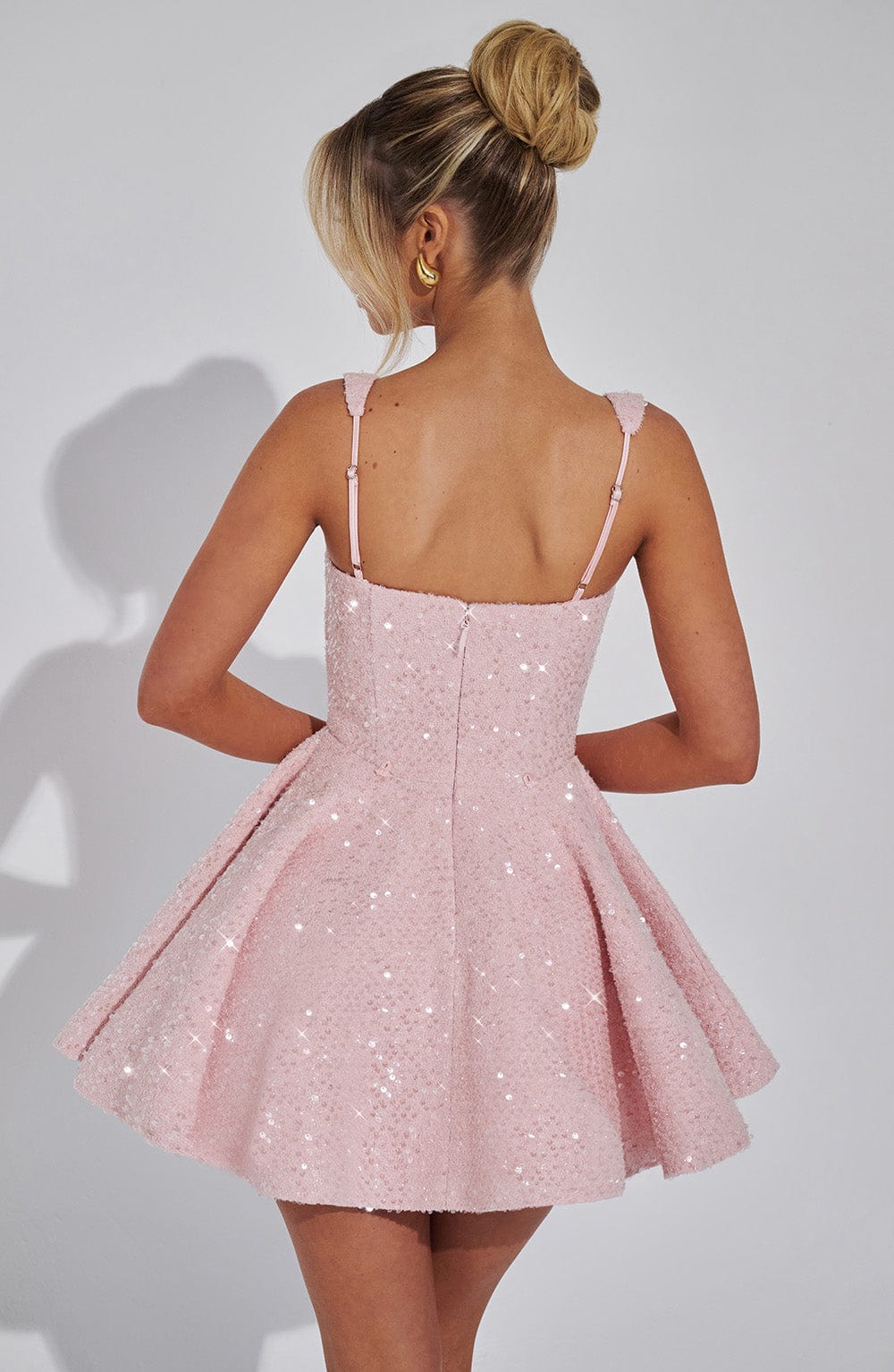 Back view of a pink sequin mini dress with a flared skirt and thin straps.