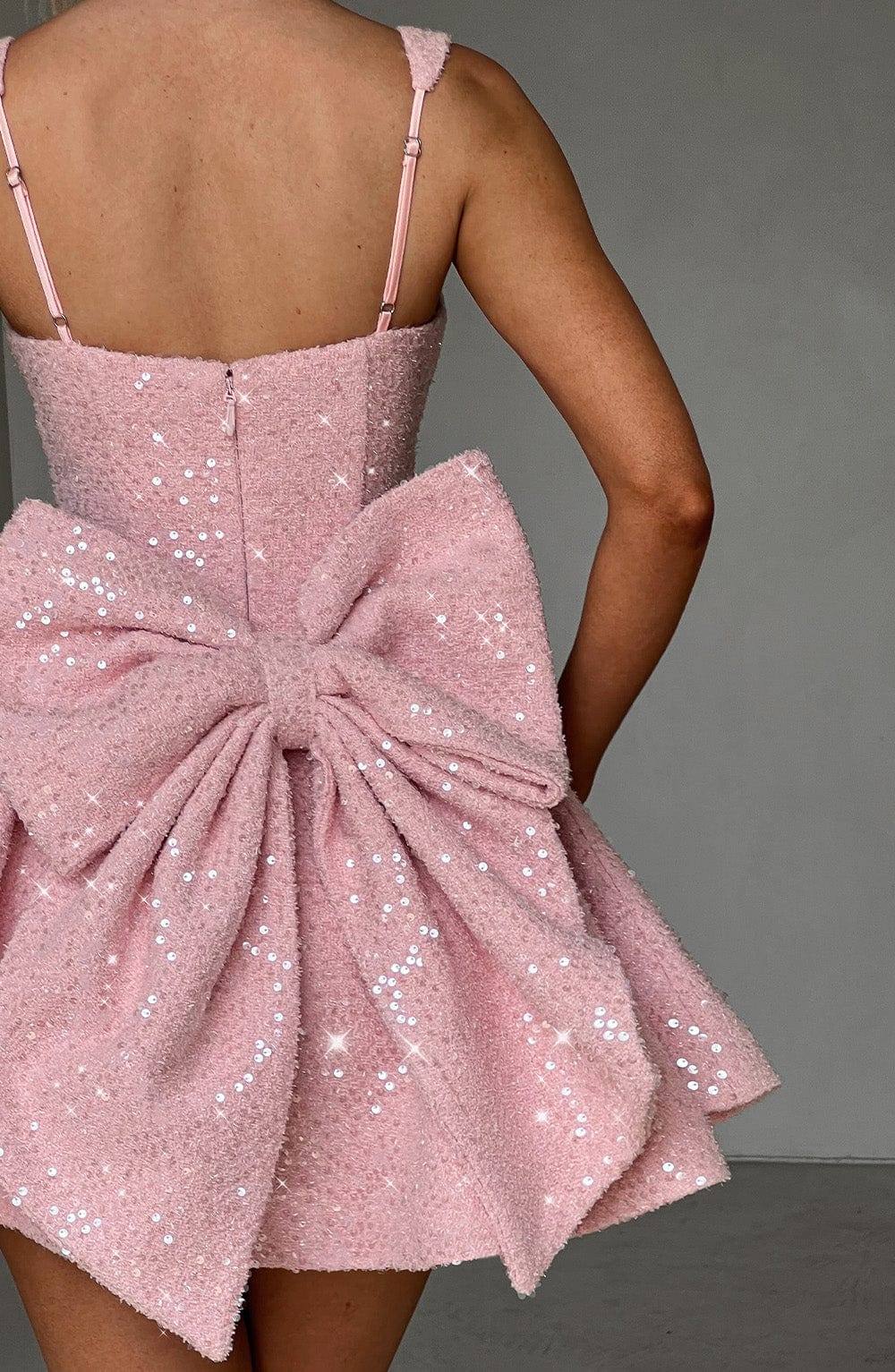 Back view of the pink Giselle mini dress featuring shimmering sequins and a large bow detail.