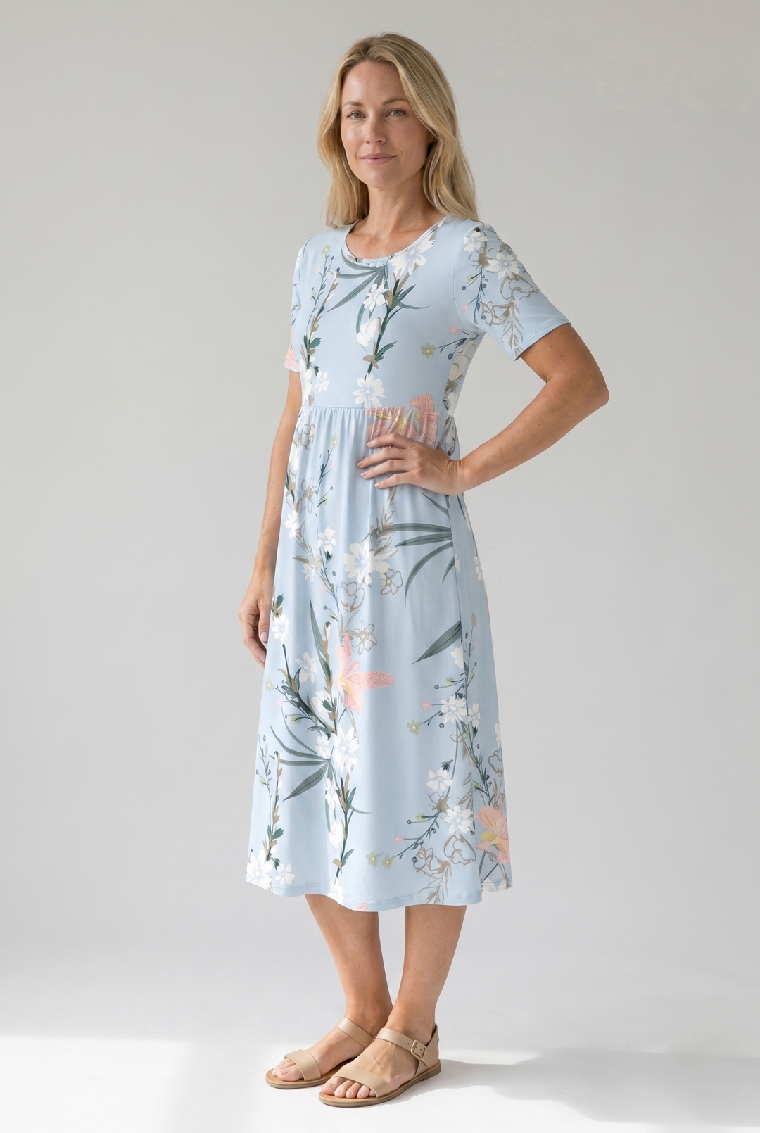 Woman in a light blue floral print midi dress with short sleeves, round neckline, and gathered waist.